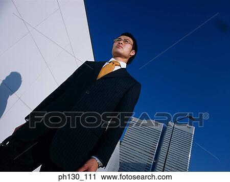 Asian Standing amidst skyscrapers View Large Photo Image Stock Image - Asian Standing amidst skyscrapers. Fotosearch