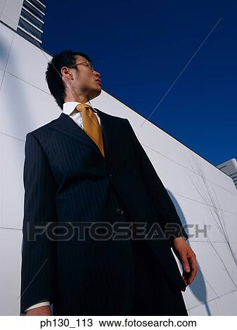 Stock Image - Asian Standing amidst skyscrapers. Fotosearch
