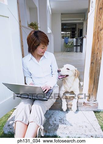Picture - Asian Woman smiling at her dog. Fotosearch