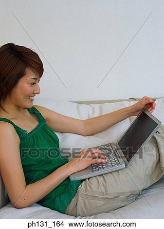 Asian Woman working on a laptop View Large Photo Image Picture - Asian Woman working on a laptop. Fotosearch