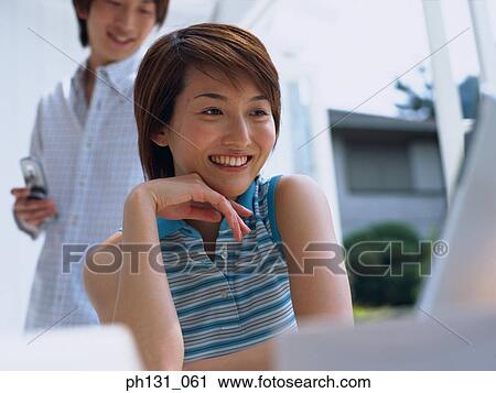 Stock Image - Asian Woman working on a laptop. Fotosearch