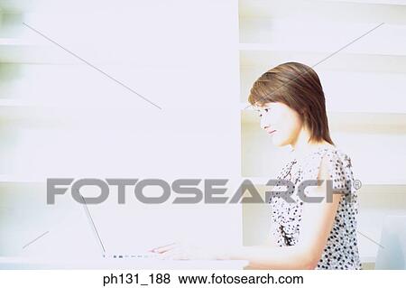 Stock Photo - Asian Woman working on a laptop. Fotosearch