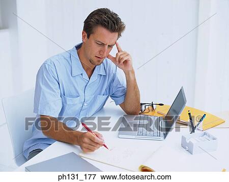 Stock Photo - Caucasian man working on a desk. Fotosearch