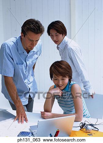 Stock Image - Group of people looking at a computer screen. Fotosearch