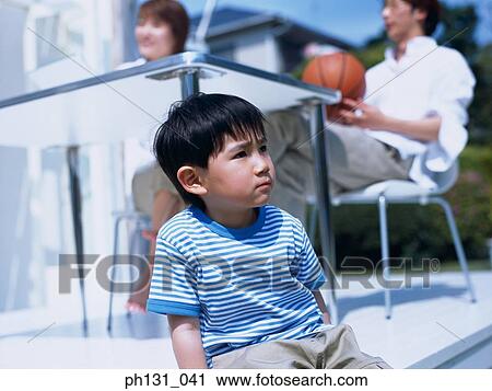 Little Asian boy sitting out with his parents View Large Photo Image Stock Image - Little Asian boy sitting out with his parents. Fotosearch