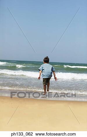 Young boy jumping in the surf View Large Photo Image Stock Image - Young boy jumping in the surf. Fotosearch