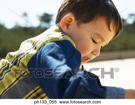 Young boy leaning forward and looking down View Large Photo Image Stock Photography - Young boy leaning forward and looking down. Fotosearch