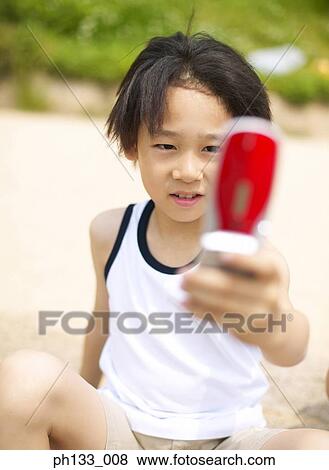 Stock Photo - Young boy operating mobile phone. Fotosearch
