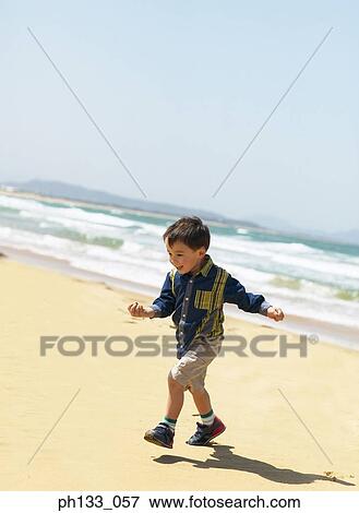 Stock Photo - Young boy playing on beach. Fotosearch