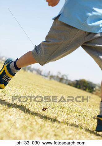 Stock Image - Young boy running on a grassy field. Fotosearch