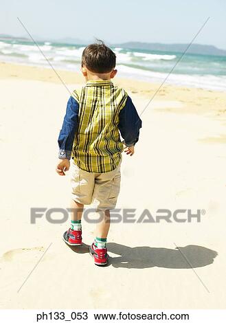 Young boy walking on beach View Large Photo Image Stock Image - Young boy walking on beach. Fotosearch