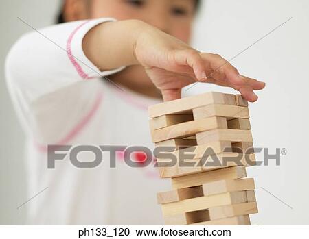 Stock Image - Young child playing with wooden building blocks. Fotosearch