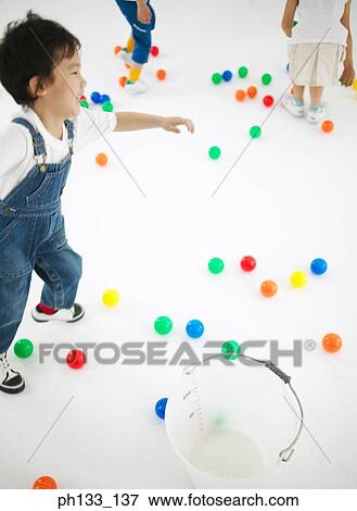 Stock Photo - Young children playing with colored plastic balls. Fotosearch