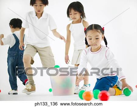 Stock Photograph - Young children playing with colored plastic balls. Fotosearch