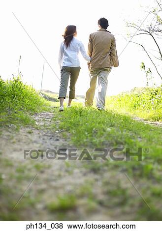 Young couple holding hands and walking View Large Photo Image Stock Photo - Young couple holding hands and walking. Fotosearch