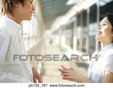 Young couple standing and talking View Large Photo Image Stock Photo - Young couple standing and talking. Fotosearch