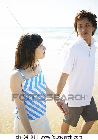 Young couple waking at beach View Large Photo Image Stock Image - Young couple waking at beach. Fotosearch