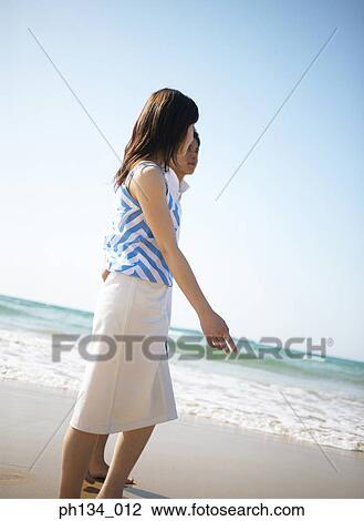 Stock Image - Young couple walking on the beach. Fotosearch