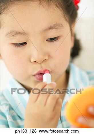 Young girl applying lipstick View Large Photo Image Stock Photo - Young girl applying lipstick. Fotosearch