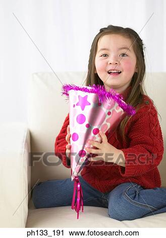Young girl holding a party hat and smiling View Large Photo Image Stock Image - Young girl holding a party hat and smiling. Fotosearch