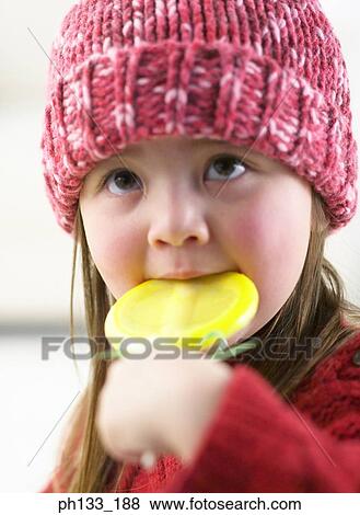 Young girl holding and eating candy View Large Photo Image Stock Photo - Young girl holding and eating candy. Fotosearch