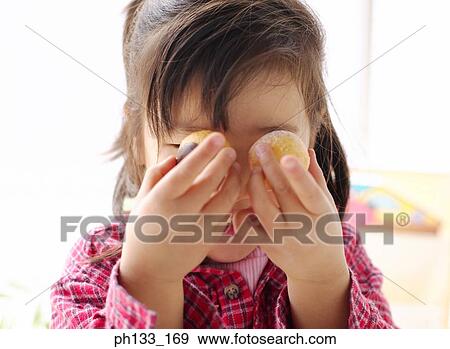 Young girl holding cookies up to her eyes View Large Photo Image Stock Photo - Young girl holding cookies up to her eyes. Fotosearch