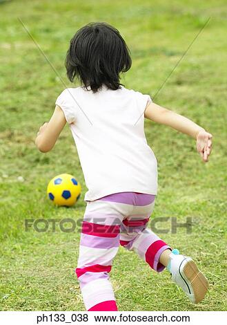 Young girl playing on grassy field View Large Photo Image Stock Photo - Young girl playing on grassy field. Fotosearch