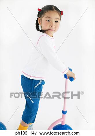 Stock Photo - Young girl standing on a scooter. Fotosearch