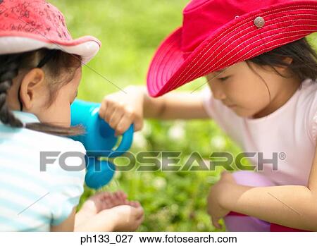 Stock Photo - Young girls washing hand with a watering can. Fotosearch