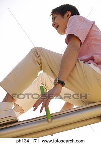 Young man on seesaw View Large Photo Image Stock Image - Young man on seesaw. Fotosearch