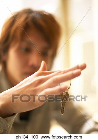 Young man sitting and holding key View Large Photo Image Stock Image - Young man sitting and holding key. Fotosearch