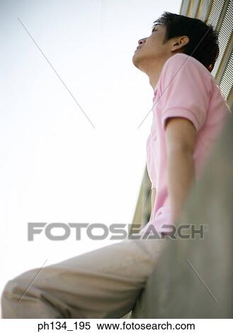 Young man sitting and looking up View Large Photo Image Stock Photography - Young man sitting and looking up. Fotosearch