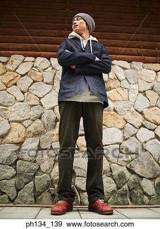 Young man standing and looking around View Large Photo Image Stock Photo - Young man standing and looking around. Fotosearch