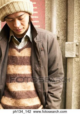 Stock Image - Young man standing and looking down. Fotosearch