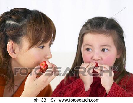 Young mother and daughter eating fruit View Large Photo Image Stock Photo - Young mother and daughter eating fruit. Fotosearch