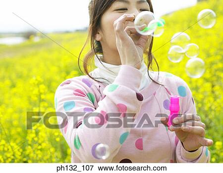 Stock Photo - Young woman blowing soap bubbles. Fotosearch