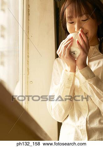 Young woman drinking from a cup View Large Photo Image Stock Photo - Young woman drinking from a cup. Fotosearch