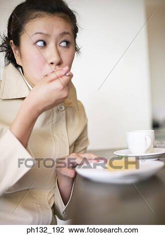 Young woman eating at a table View Large Photo Image Stock Image - Young woman eating at a table. Fotosearch