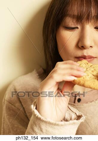 Young woman eating cookie View Large Photo Image Picture - Young woman eating cookie. Fotosearch