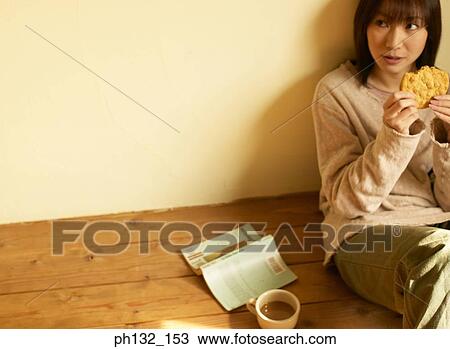 Stock Image - Young woman eating cookie. Fotosearch