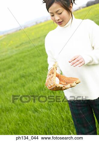 Young woman holding a baseball and wearing a baseball mitt View Large Photo Image Picture - Young woman holding a baseball and wearing a baseball mitt. Fotosearch