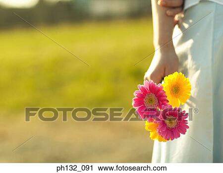 Young woman holding bunch of flowers View Large Photo Image Stock Image - Young woman holding bunch of flowers. Fotosearch