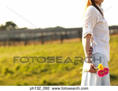 Stock Image - Young woman holding flowers. Fotosearch