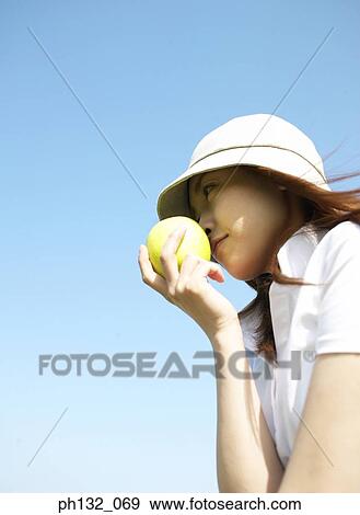 Young woman holding fruit to her face View Large Photo Image Stock Photo - Young woman holding fruit to her face. Fotosearch
