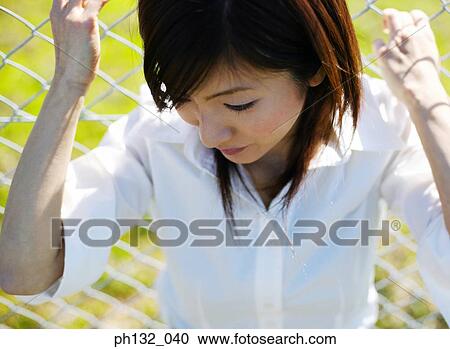 Young woman holding on to a chainlink fence View Large Photo Image Stock Image - Young woman holding on to a chainlink fence. Fotosearch