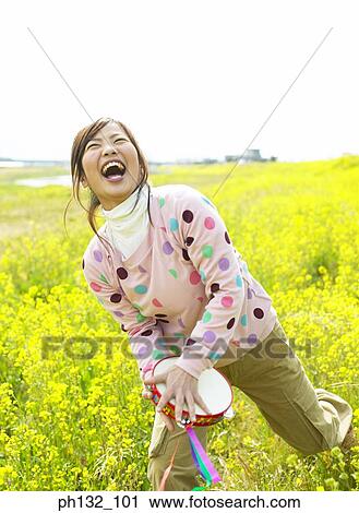 Young woman in a meadow holding a musical instrument View Large Photo Image Stock Image - Young woman in a meadow holding a musical instrument. Fotosearch