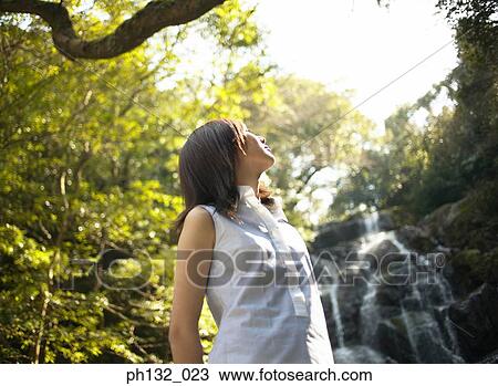 Young woman in front of a waterfall looking upwards View Large Photo Image Stock Image - Young woman in front of a waterfall looking upwards. Fotosearch