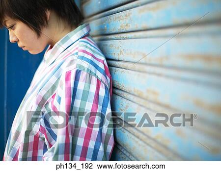 Young woman leaning against a shutter View Large Photo Image Stock Image - Young woman leaning against a shutter. Fotosearch