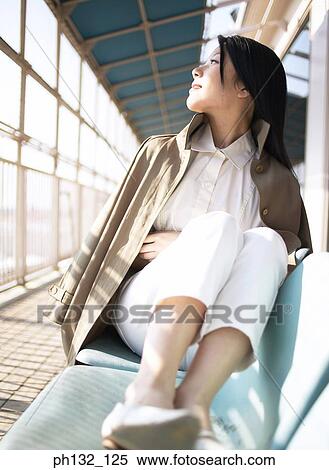 Stock Photography - Young woman lying on couch in waiting room. Fotosearch