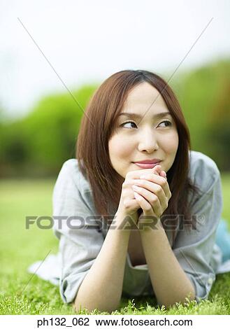 Young woman lying on the grass View Large Photo Image Stock Image - Young woman lying on the grass. Fotosearch
